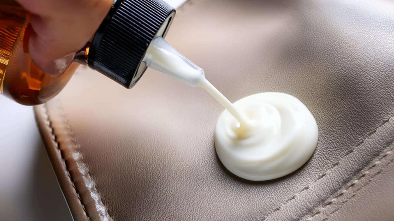 Liquid chemical being dispensed onto a leather surface during a product application process.