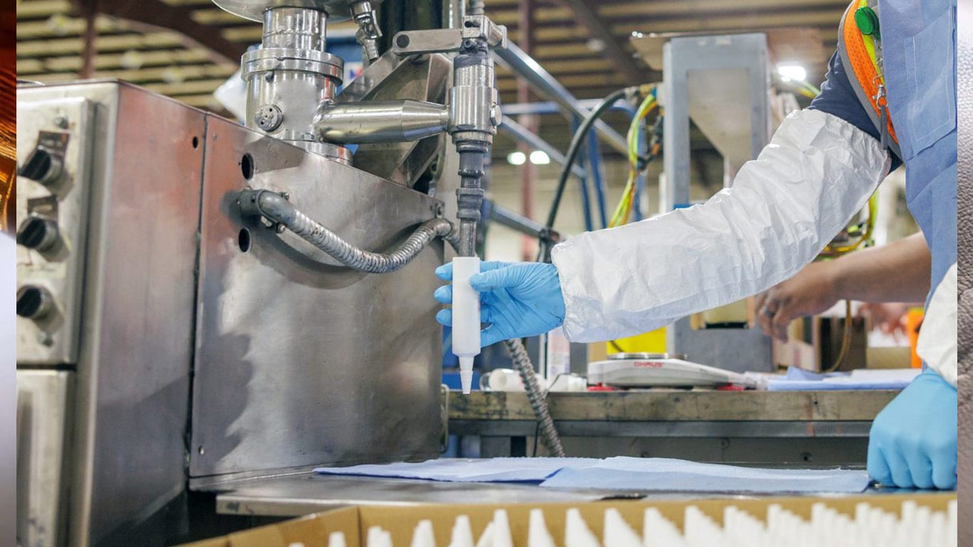 Technician operating industrial equipment during a chemical manufacturing or packaging process.